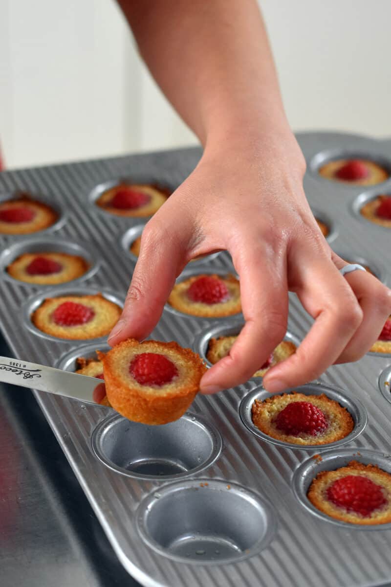 Removing a paleo raspberry financier from a muffin pan.