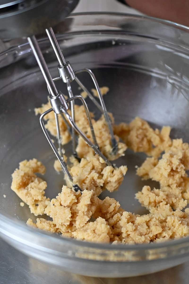 A hand mixer is creaming maple sugar in ghee to make paleo thumbprint cookies.