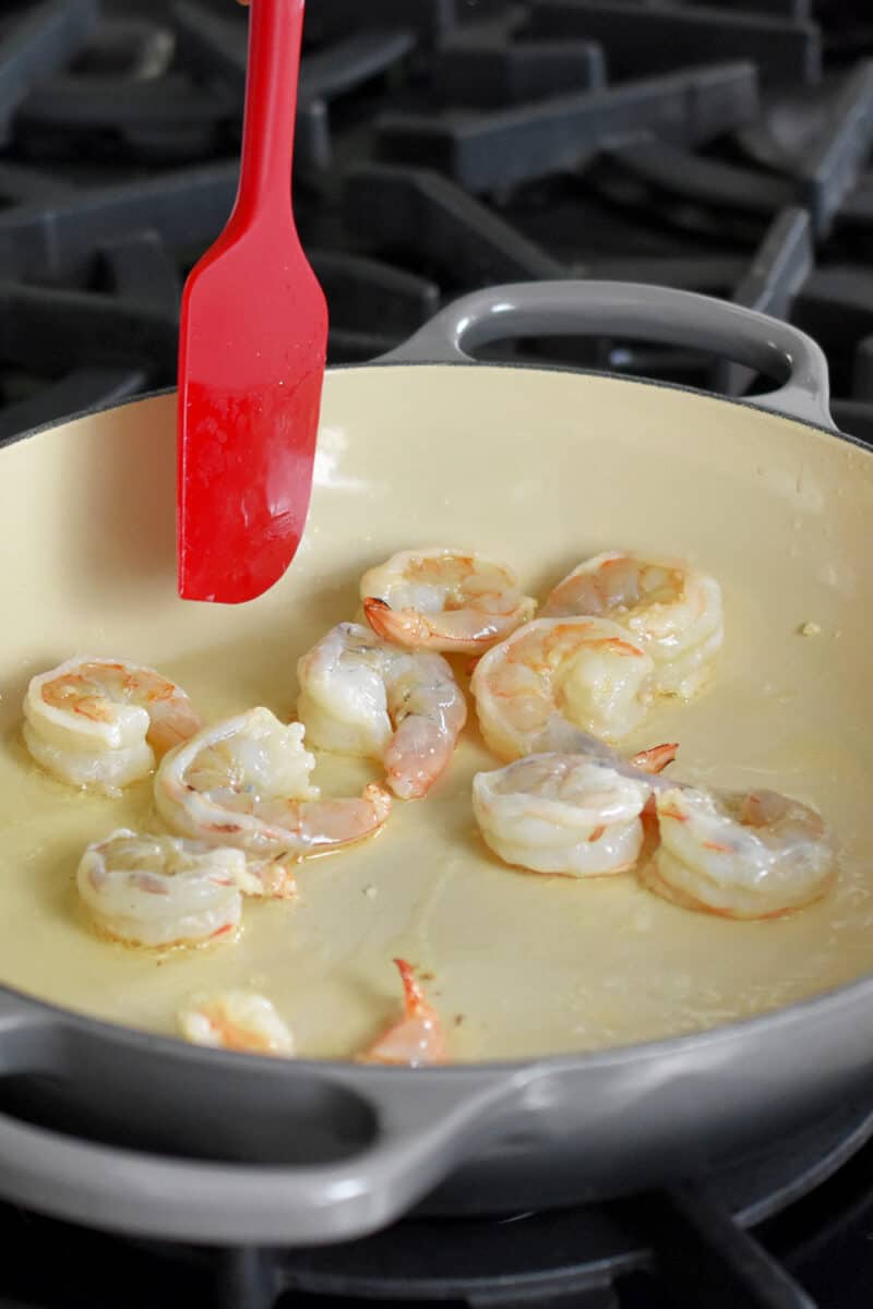 Shrimp being sautéed in a enameled cast iron skillet