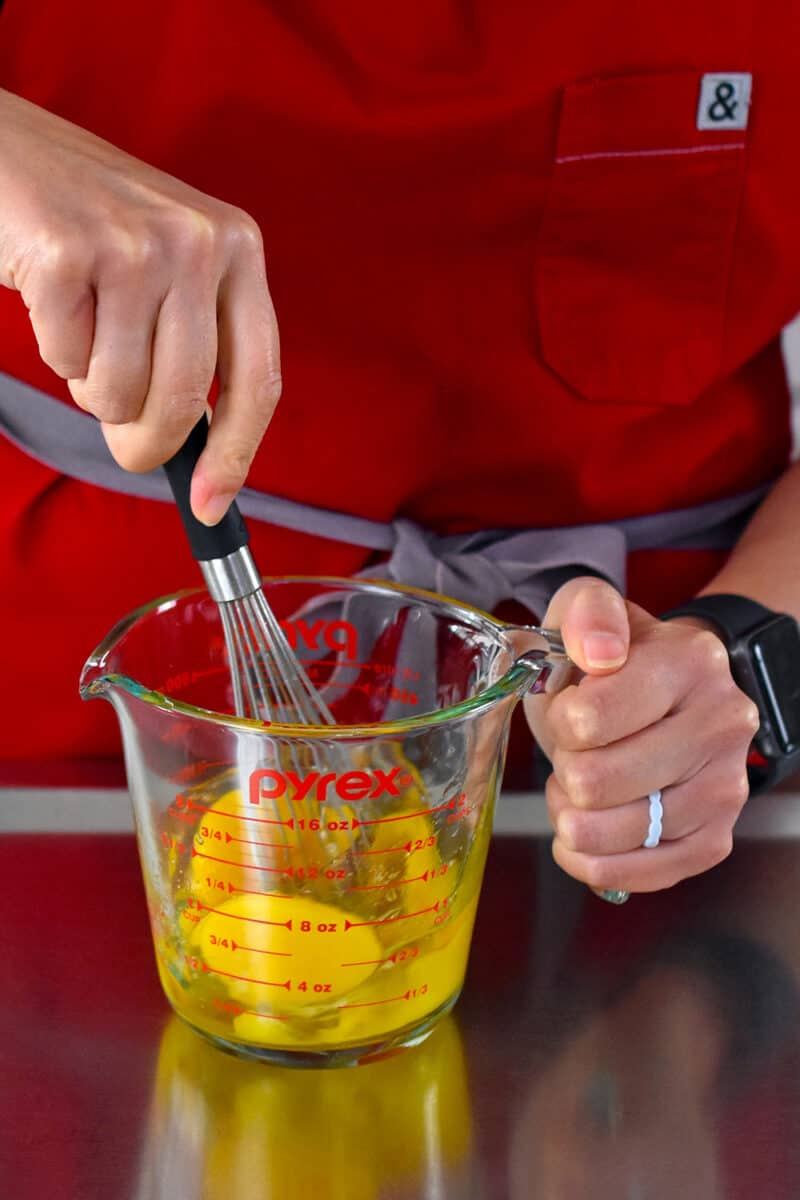 Whisking raw eggs in a clear liquid measuring cup