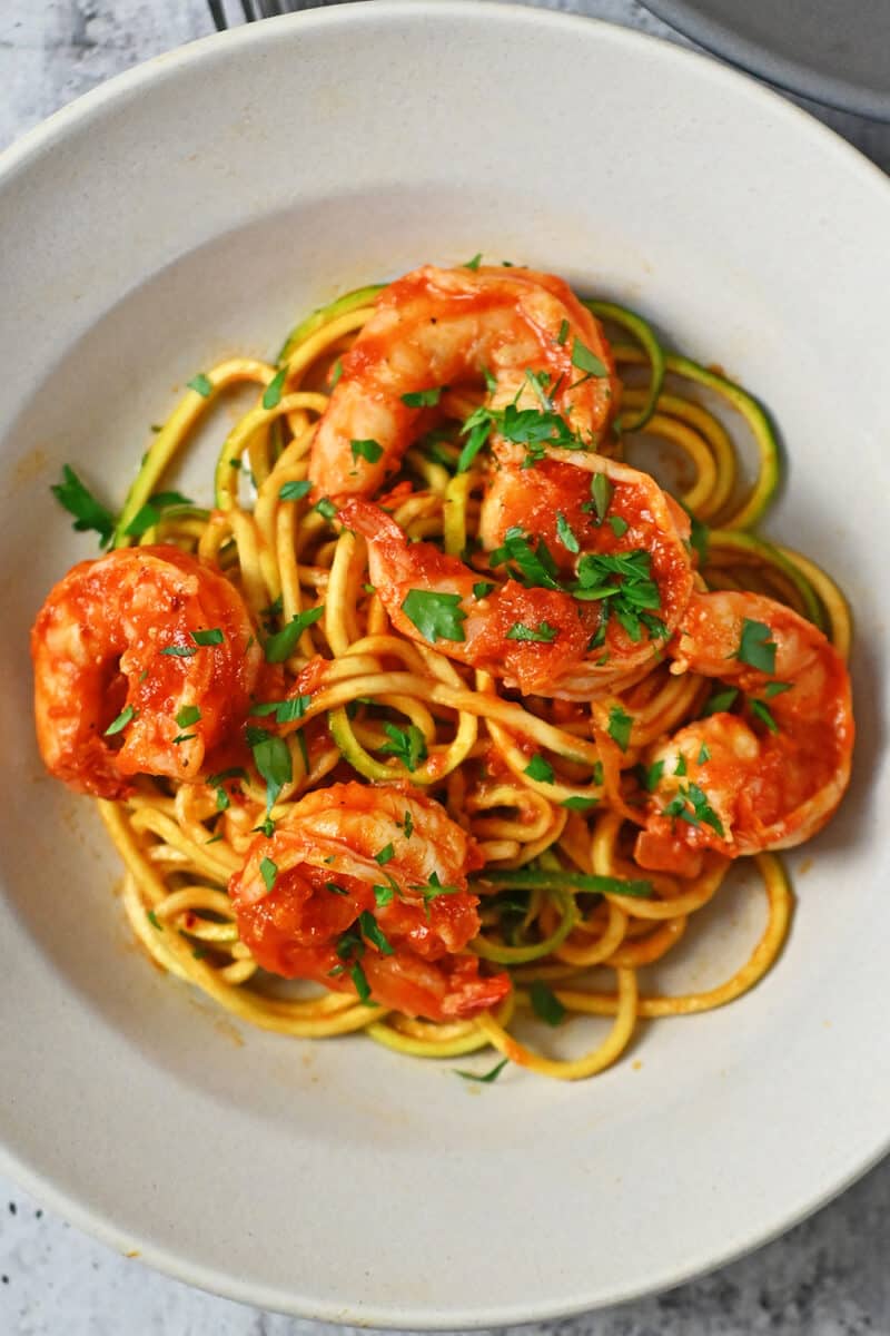 An overhead shot of a shallow bowl filled with Whole30, paleo, and keto spicy shrimp pasta with marinara sauce and zucchini noodles.