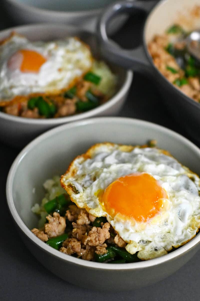 Two bowls with Thai Basil Chicken topped with crispy fried egg