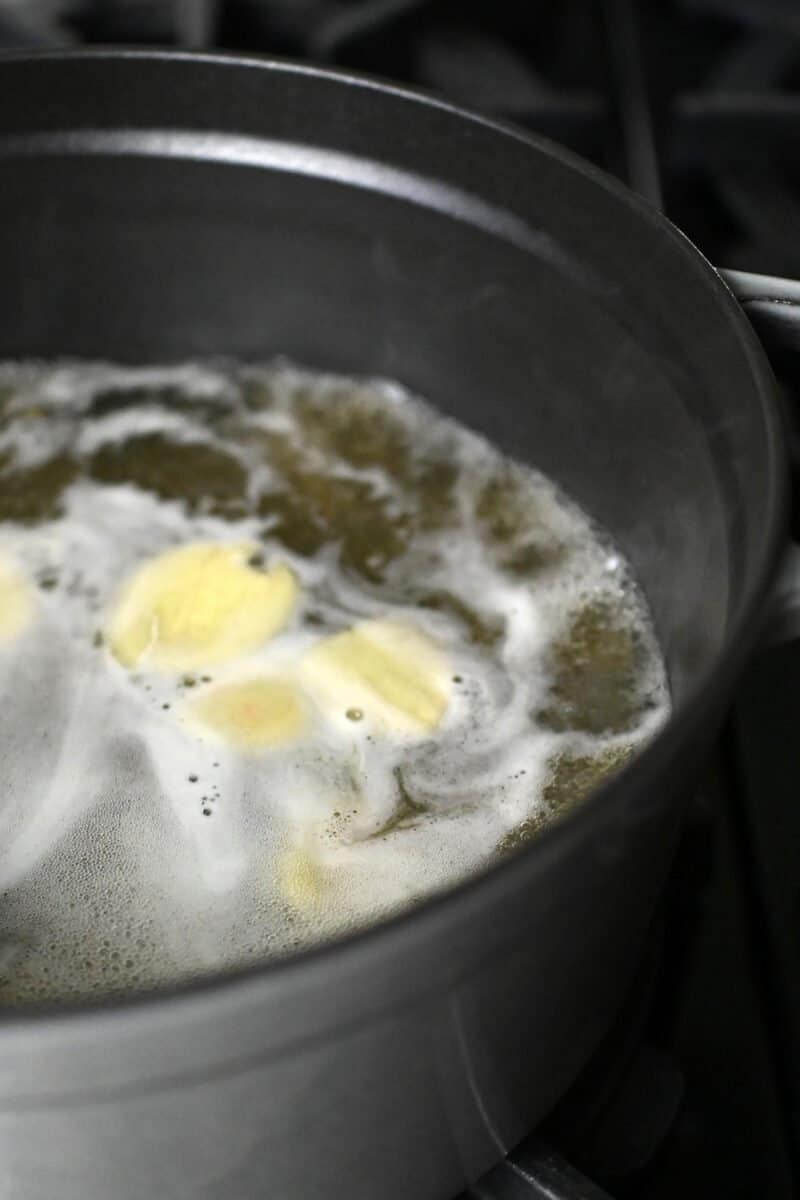 Chicken broth with ginger slices is simmering in a large pot.