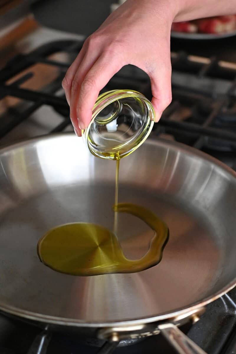Adding some avocado oil into a hot stainless steel pan.