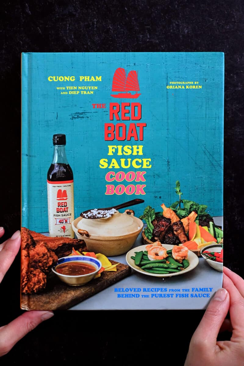 Two hands are holding the Red Boat Fish Sauce cookbook.