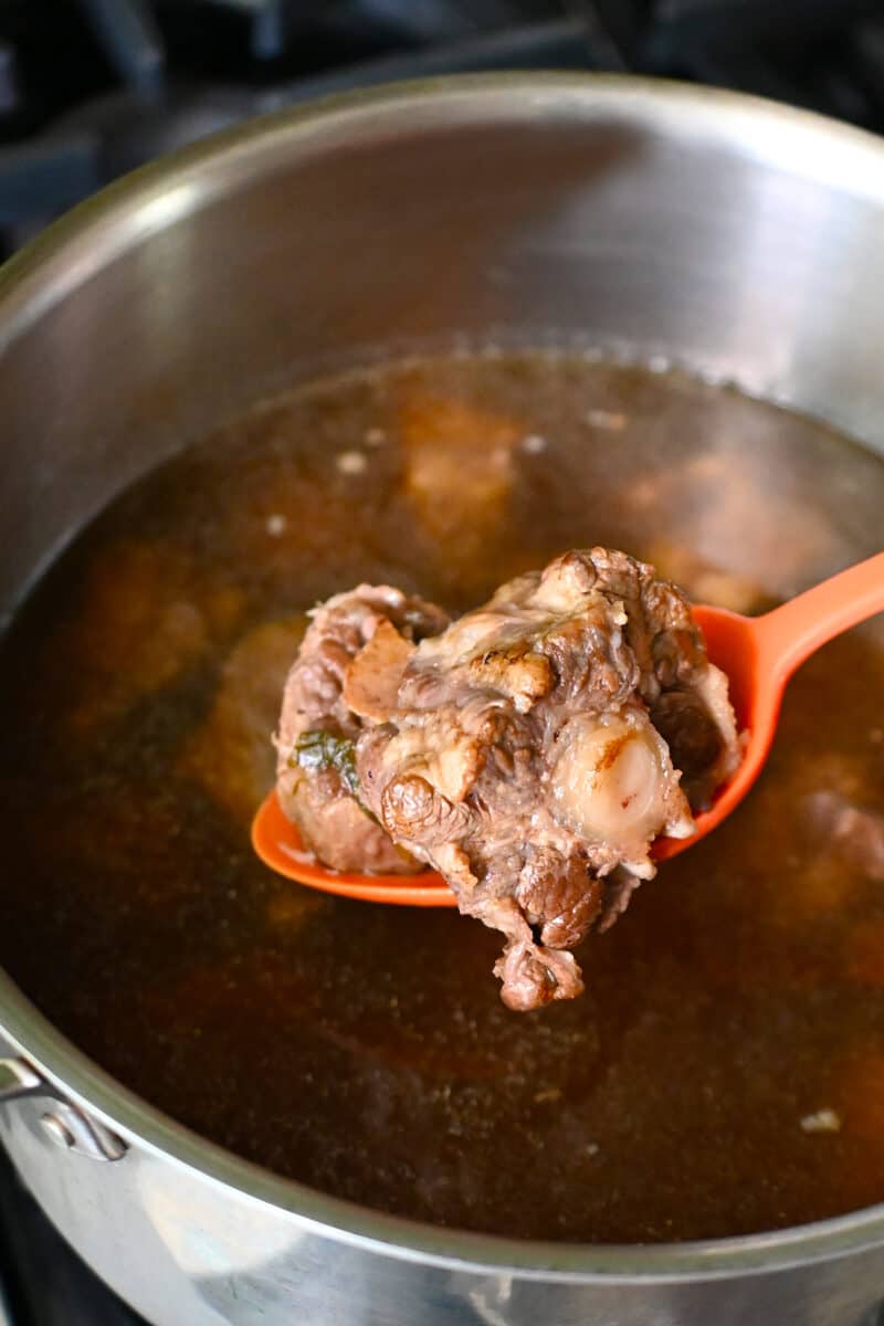 Adding the oxtails back into the oxtail soup.
