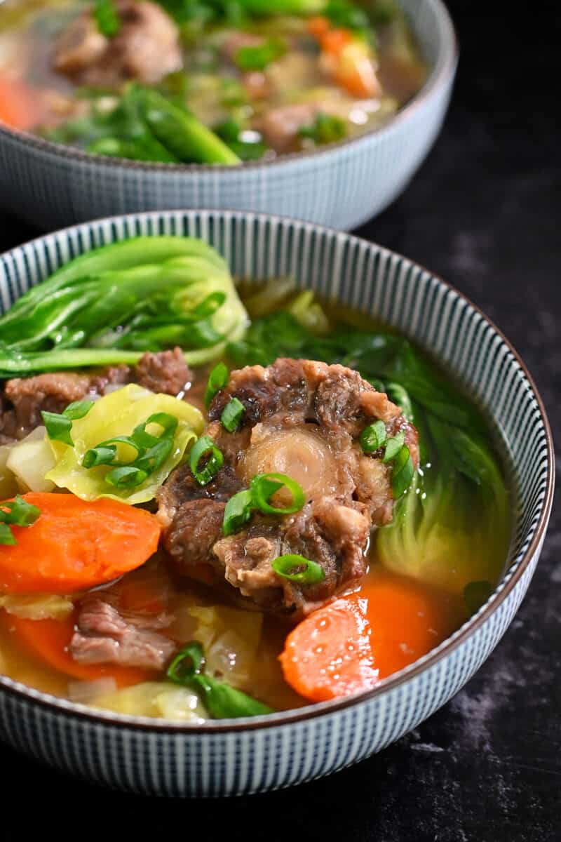 Closeup side view of two bowls of oxtail soup.