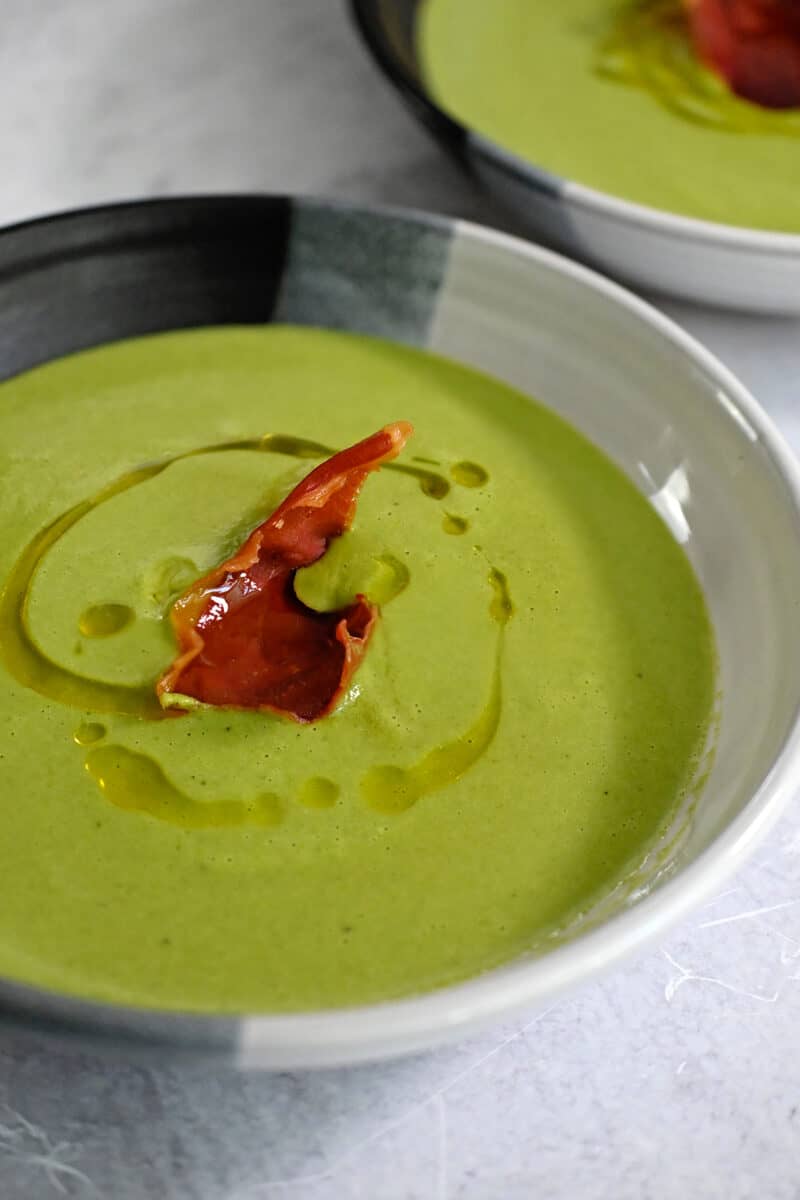 A closeup shot of pea soup with crispy prosciutto on top