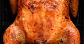 An overhead shot of a golden brown air fryer whole chicken in an air fryer basket.