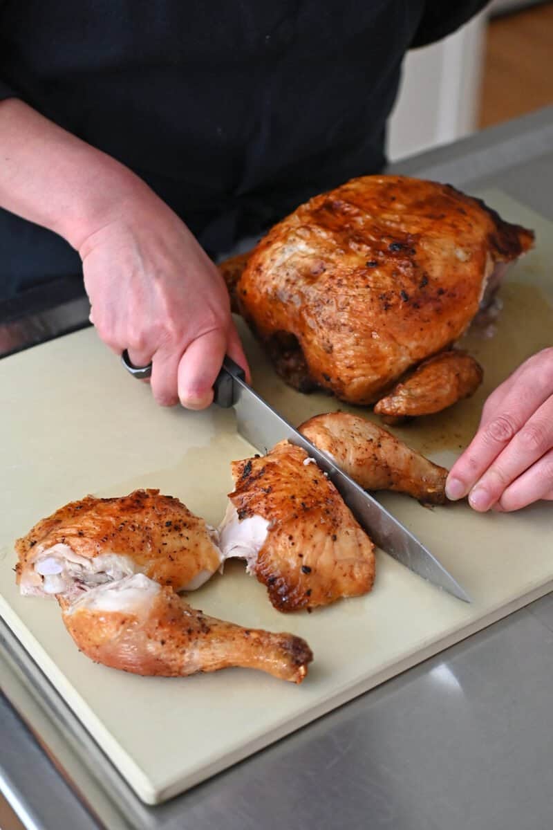 Cutting up an air fryer whole chicken on a cutting board.