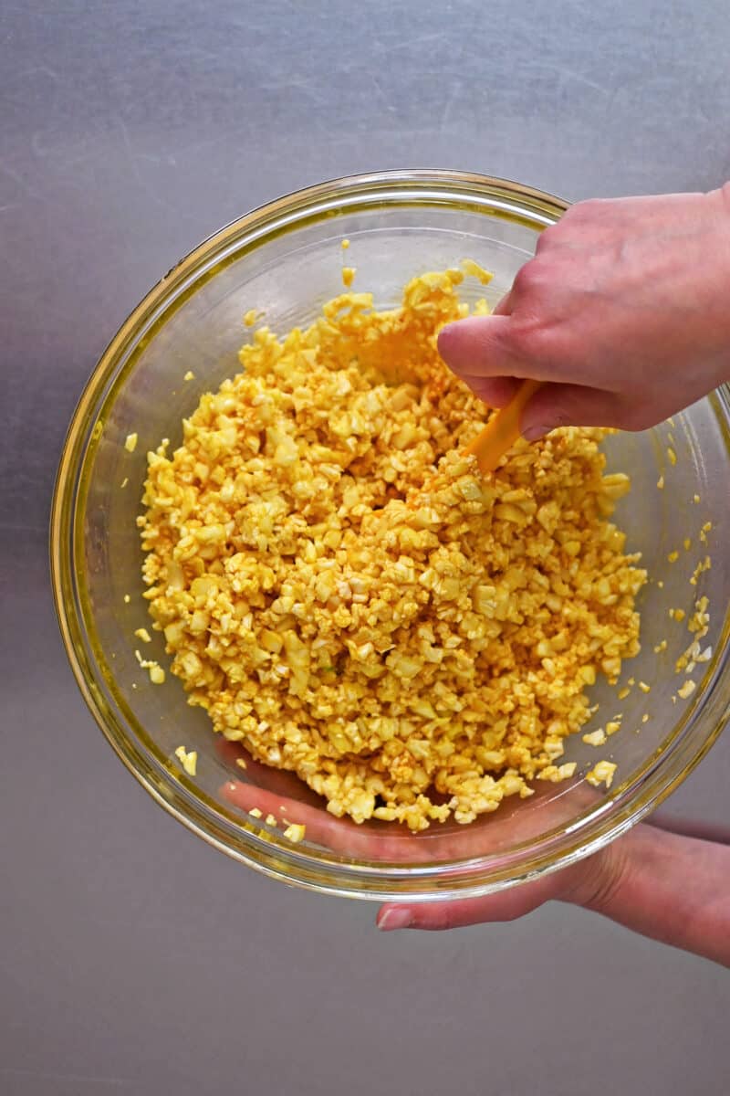An overhead shot of cauliflower rice coated with egg yolks and seasoning to make golden cauliflower fried rice.