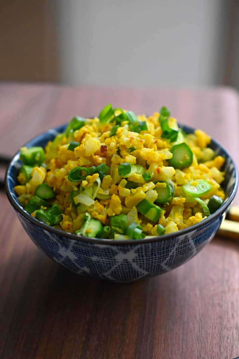 A bowl filled with golden cauliflower fried rice.