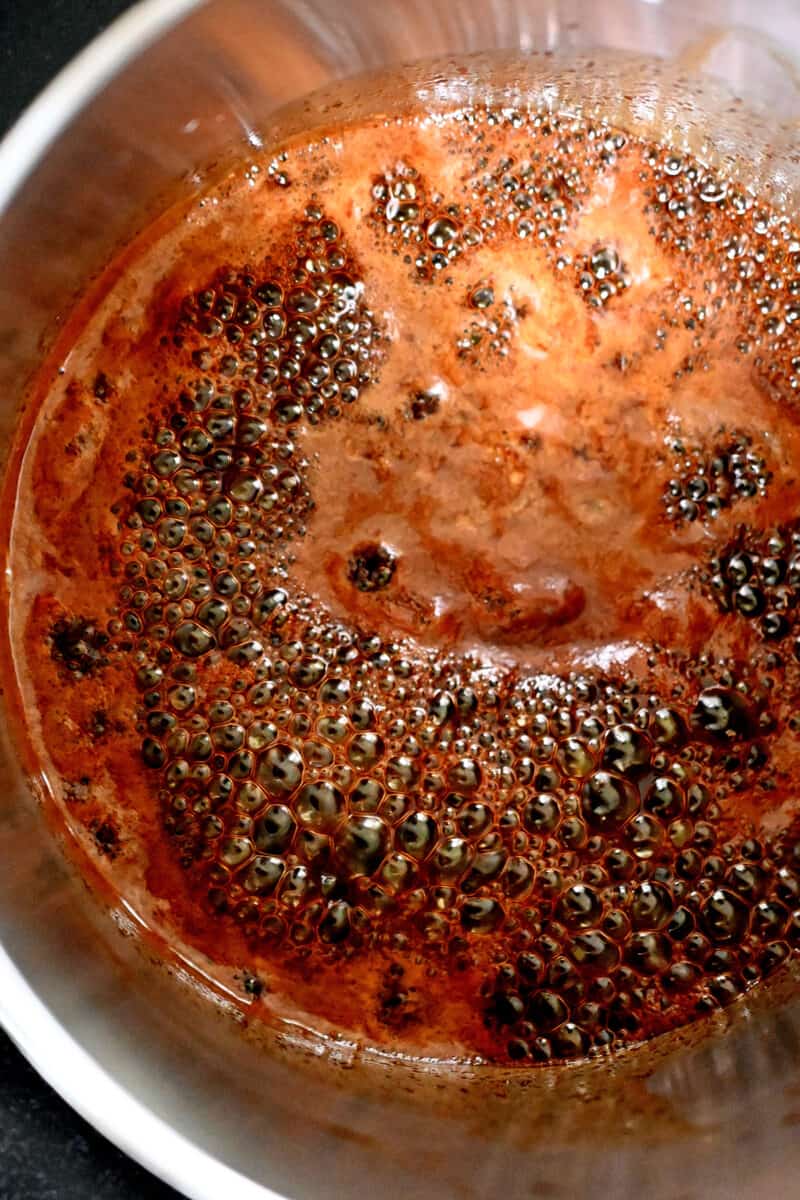 An overhead shot of a small saucepan filled with simmering honey sriracha glaze.