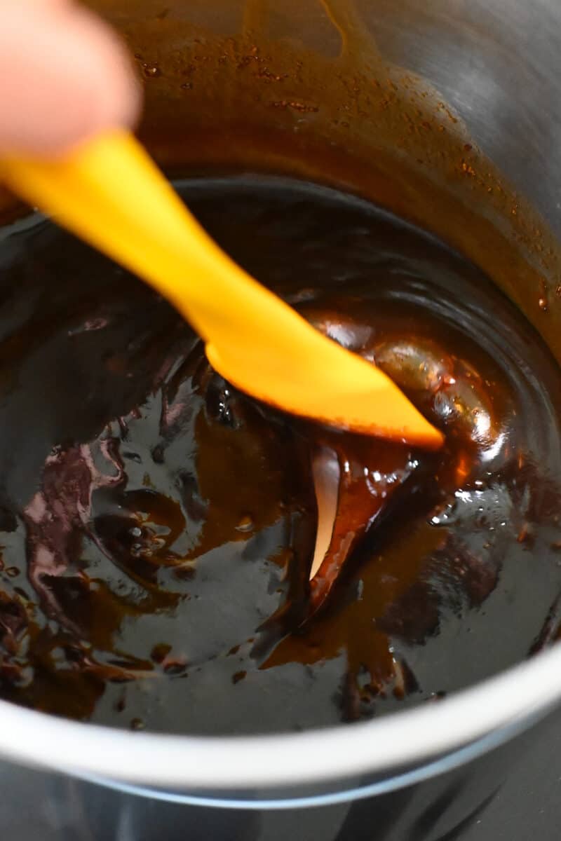 A closeup of the honey sriracha sauce in the saucepan, slightly thickened.