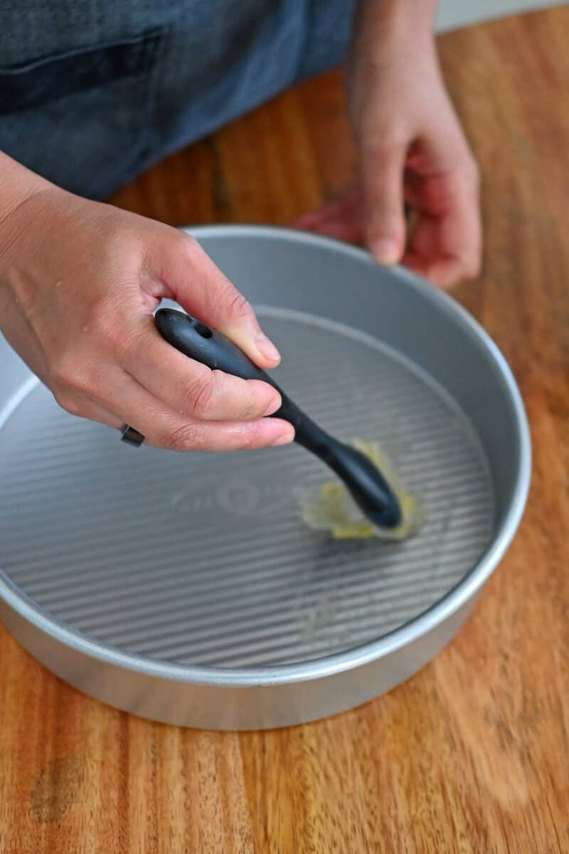 Brushing a light coating of ghee in a 9-inch round cake pan.