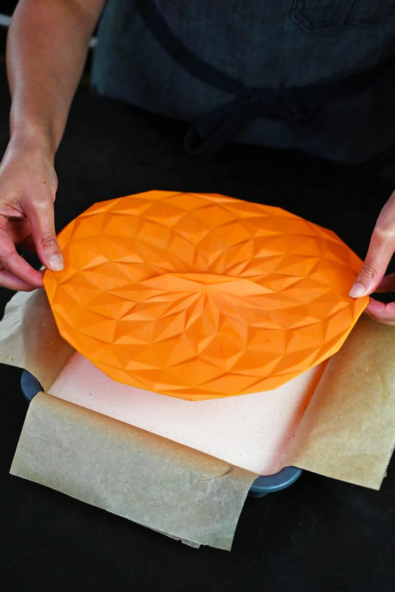 Covering a pan of coconut cream bars with an orange silicone lid. 