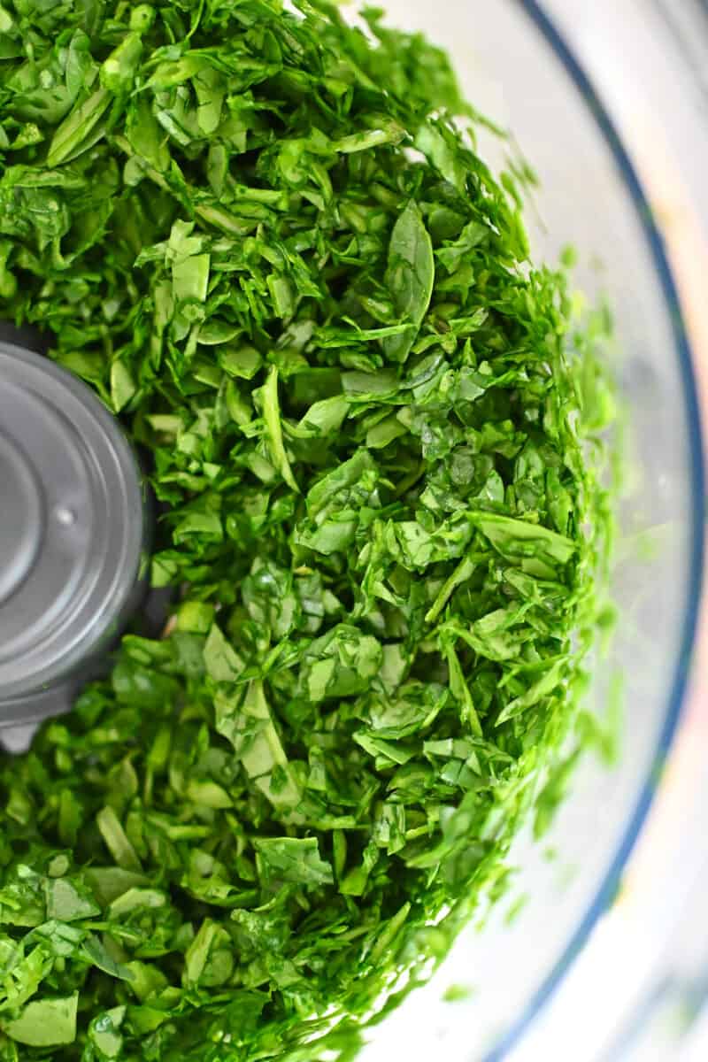 An overhead shot of chopped spinach in a food processor.
