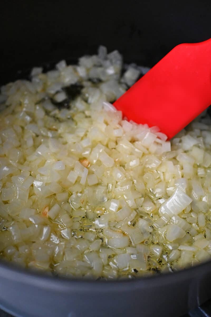 Lightly browned chopped onions being cooked in a large dutch oven.