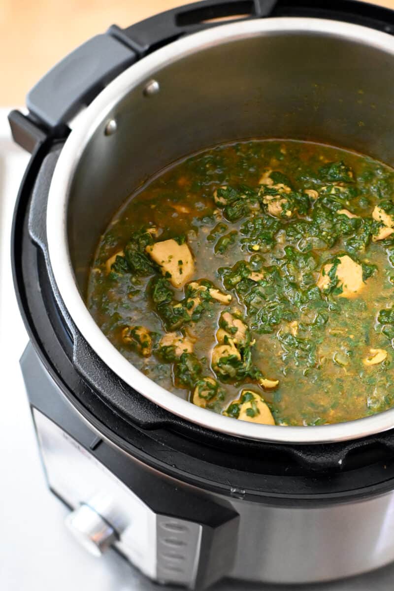 An open Instant Pot filled with a green chicken curry, Chicken Saag.