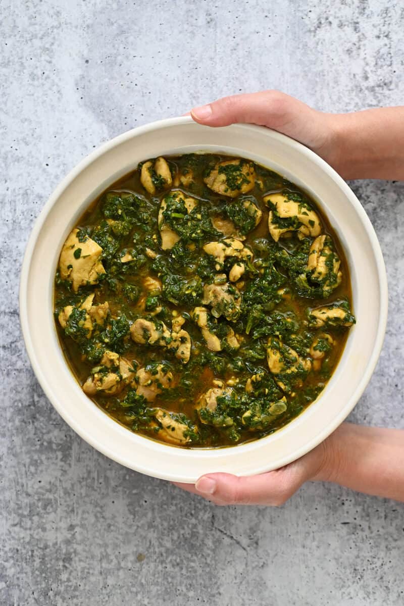 An overhead shot of a bowl containing chicken saag, an Indian curry with spinach and chicken.