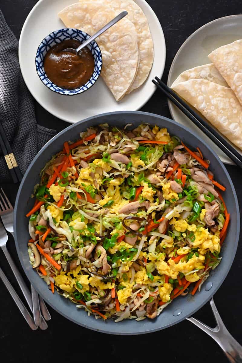 An overhead shot of a big skillet of Moo Shu Chicken, with gluten free and Whole30 hoisin sauce and wrappers.