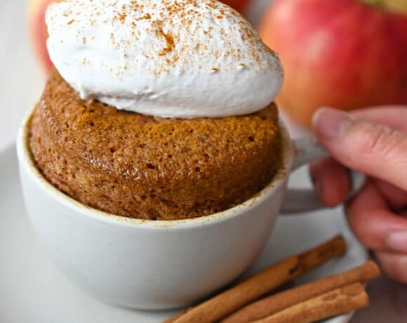 A gluten free and paleo apple mug cake topped with whipped coconut cream.