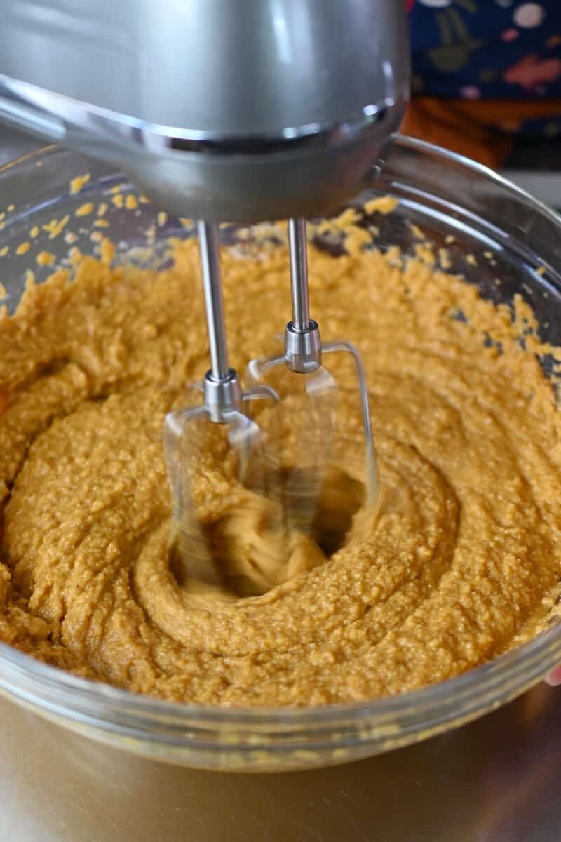 A hand mixer is mixing the batter for paleo and gluten free pumpkin bars.