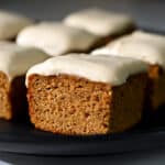 A side view of a paleo and gluten free pumpkin bar topped with a dairy-free cream cheese frosting.
