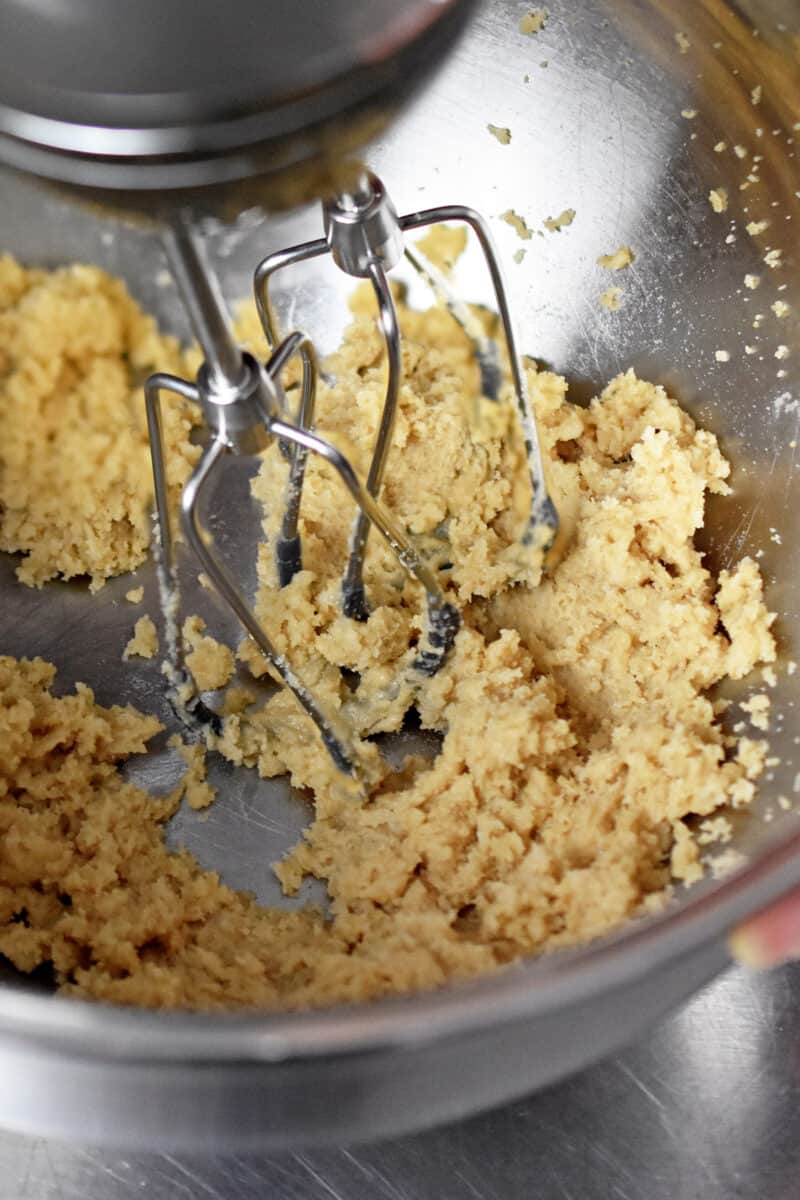 Closeup showing a hand mixer combining maple sugar with softened coconut oil.