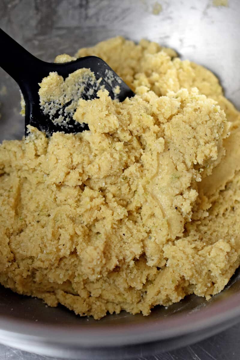 A black silicone spatula has mixed the raw cookie dough together.