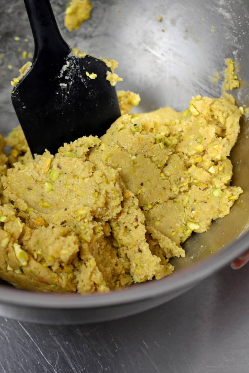 Raw cookie dough in a bowl with finely chopped pistachios mixed in.