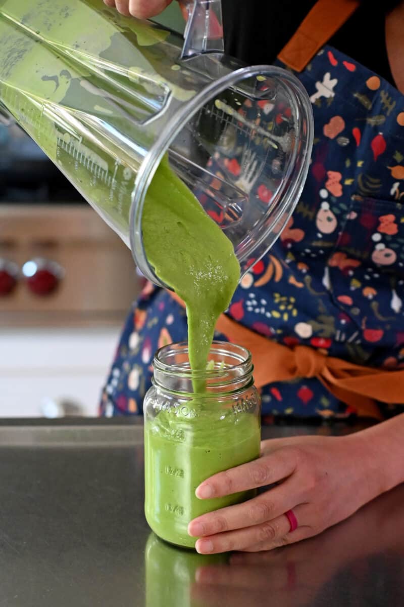Pouring Green Goddess dressing into a mason jar.