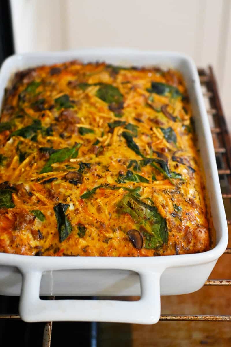 A paleo and gluten free sausage breakfast casserole on an oven rack in an open oven.