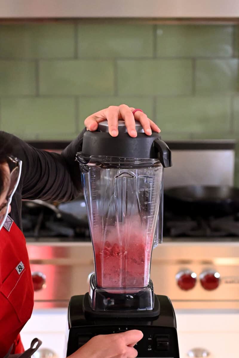 A Vitamix blender is pulverizing freeze dried strawberries into a fine powder.