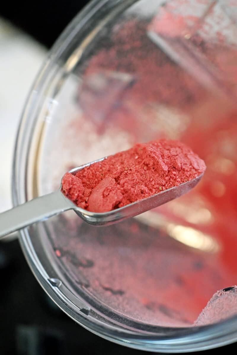 A tablespoon of freeze-dried strawberry powder is being removed from a blender.