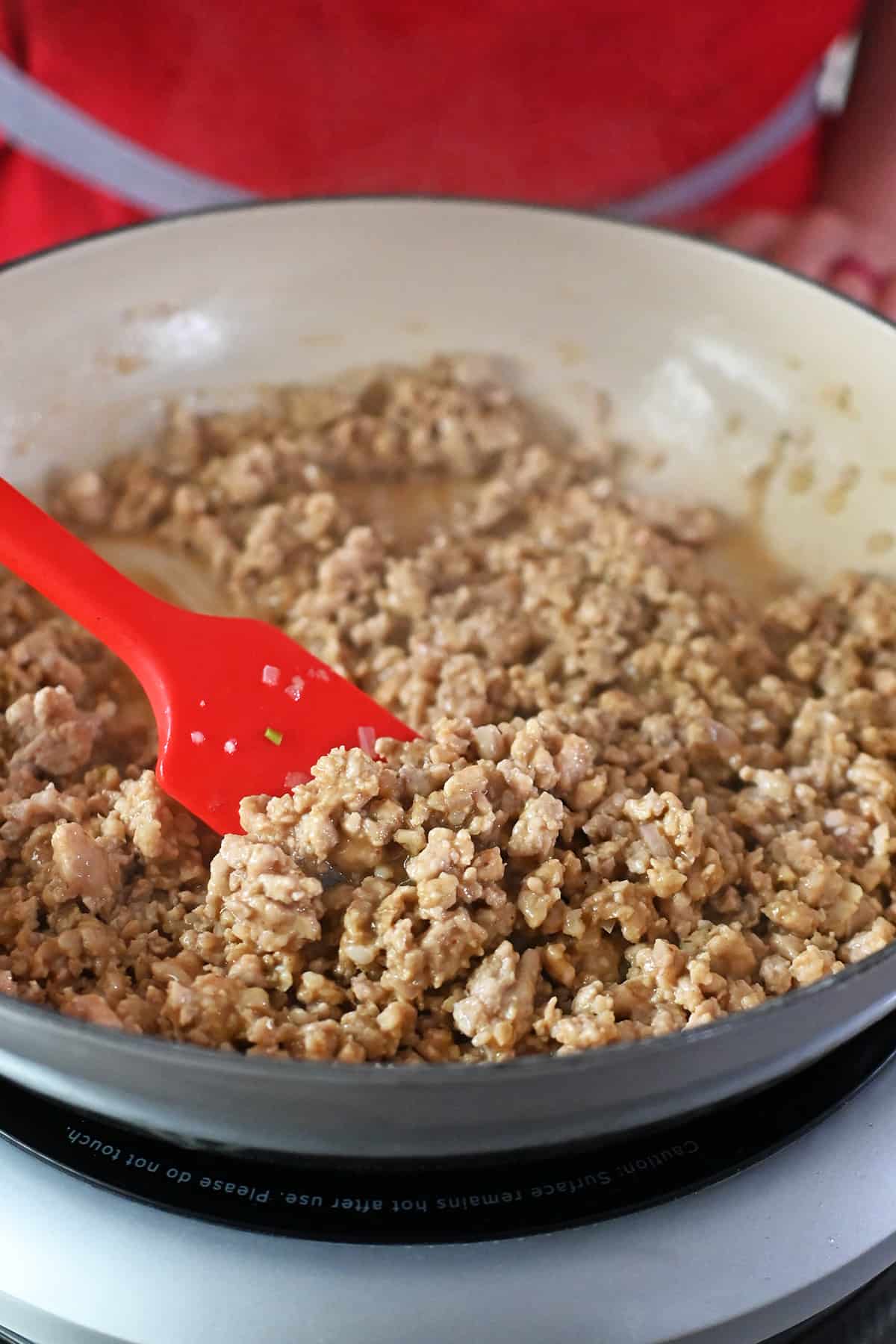 A skillet filled with ground chicken in a thickened brown sauce.