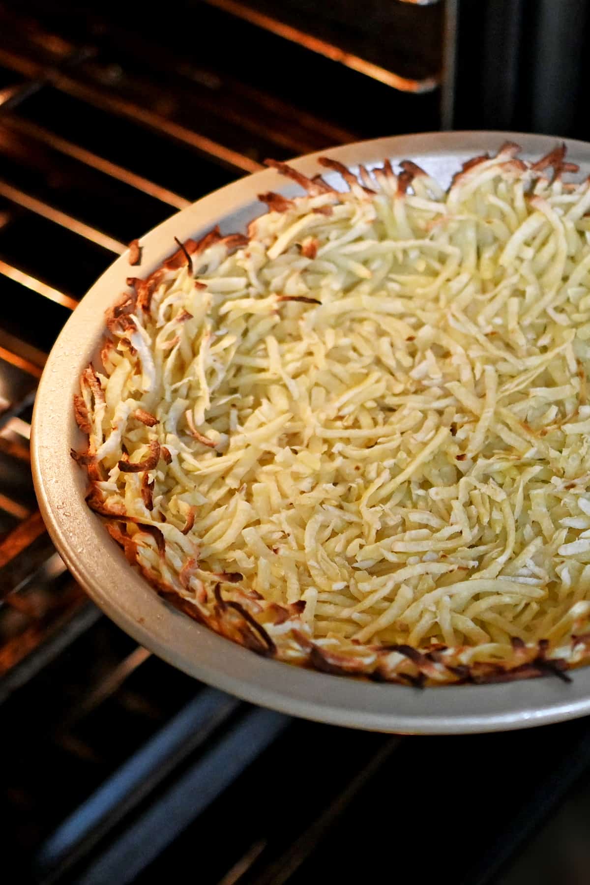 A baked shredded potato crust coming out of the oven.