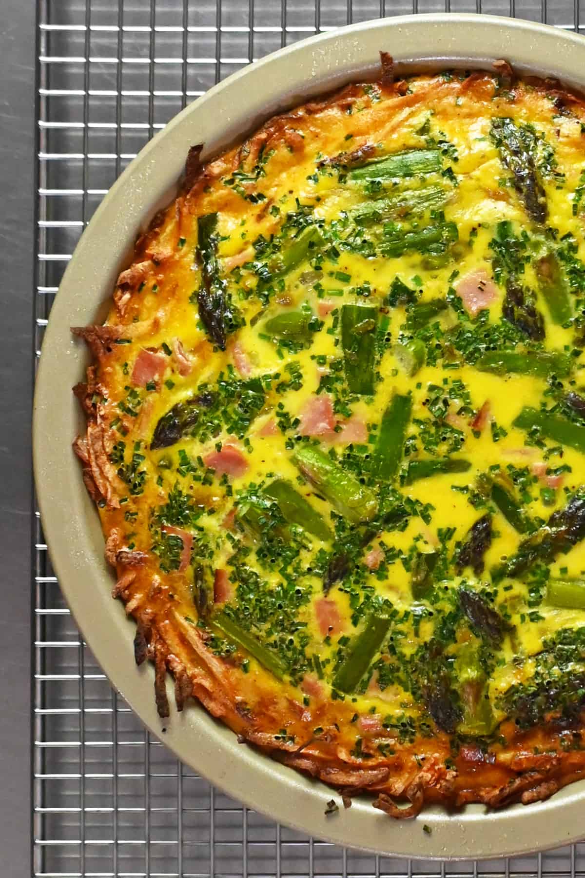 A paleo and Whole30 asparagus quiche is cooling on a wire rack.