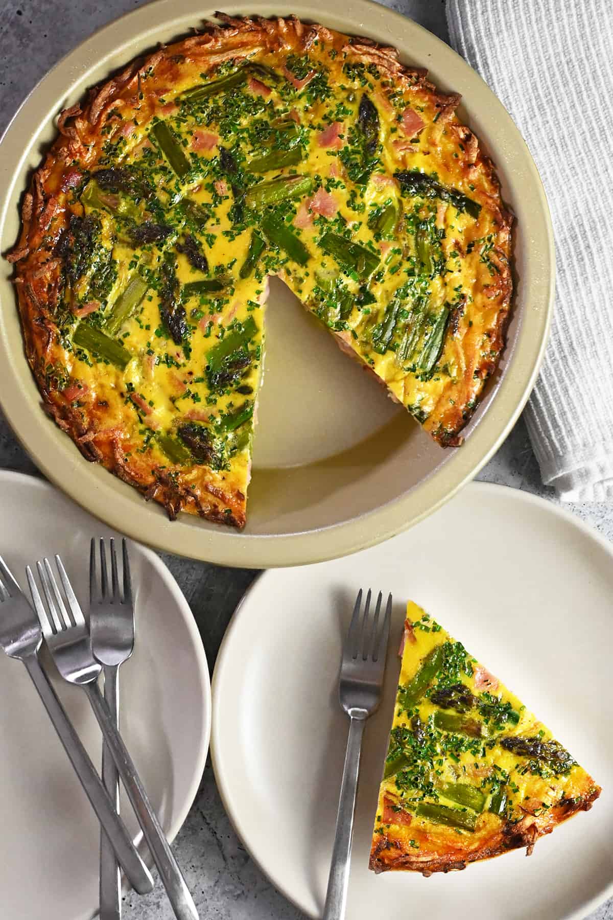 An overhead shot of a paleo asparagus quiche with a slice taken out and put on a serving plate.