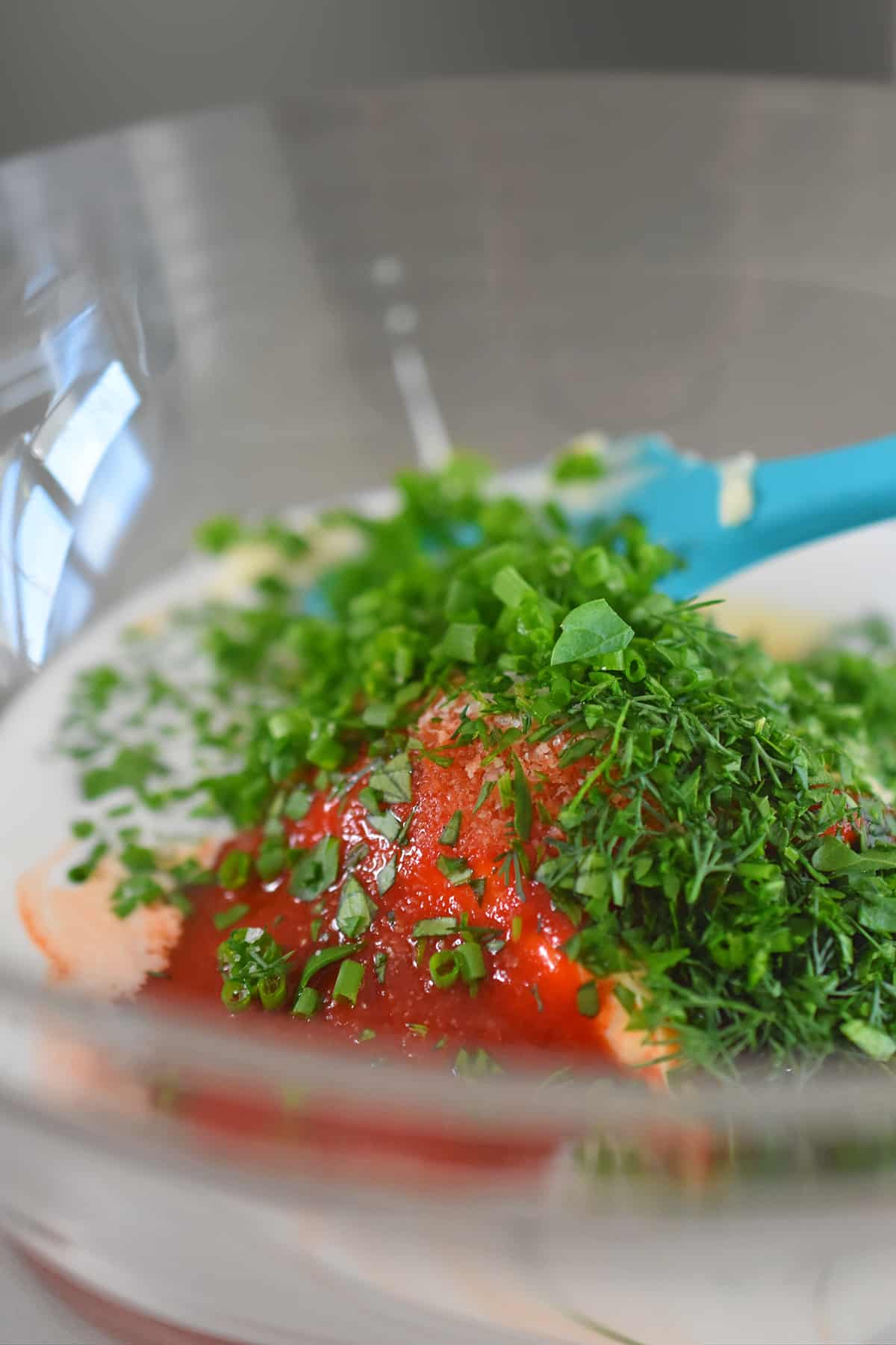 A closeup of a bowl filled with the ingredients to make a paleo sriracha ranch dressing before being mixed together.