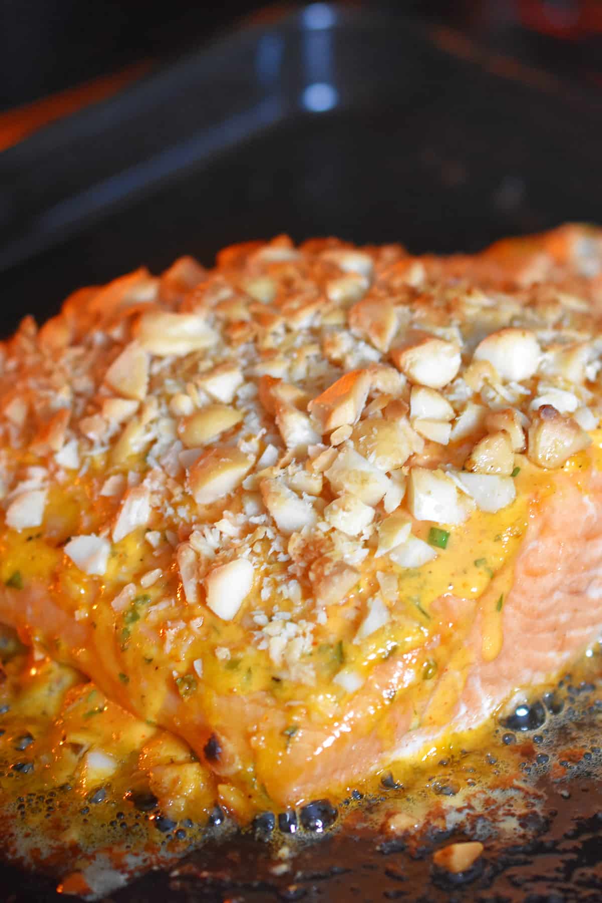 A closeup of a macadamia crusted sriracha ranch salmon fillet baking in the oven.