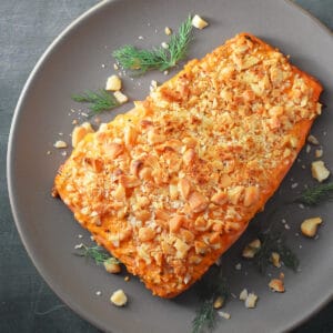 An overhead shot of macadamia crusted salmon with sriracha ranch dressing on a beige plate.