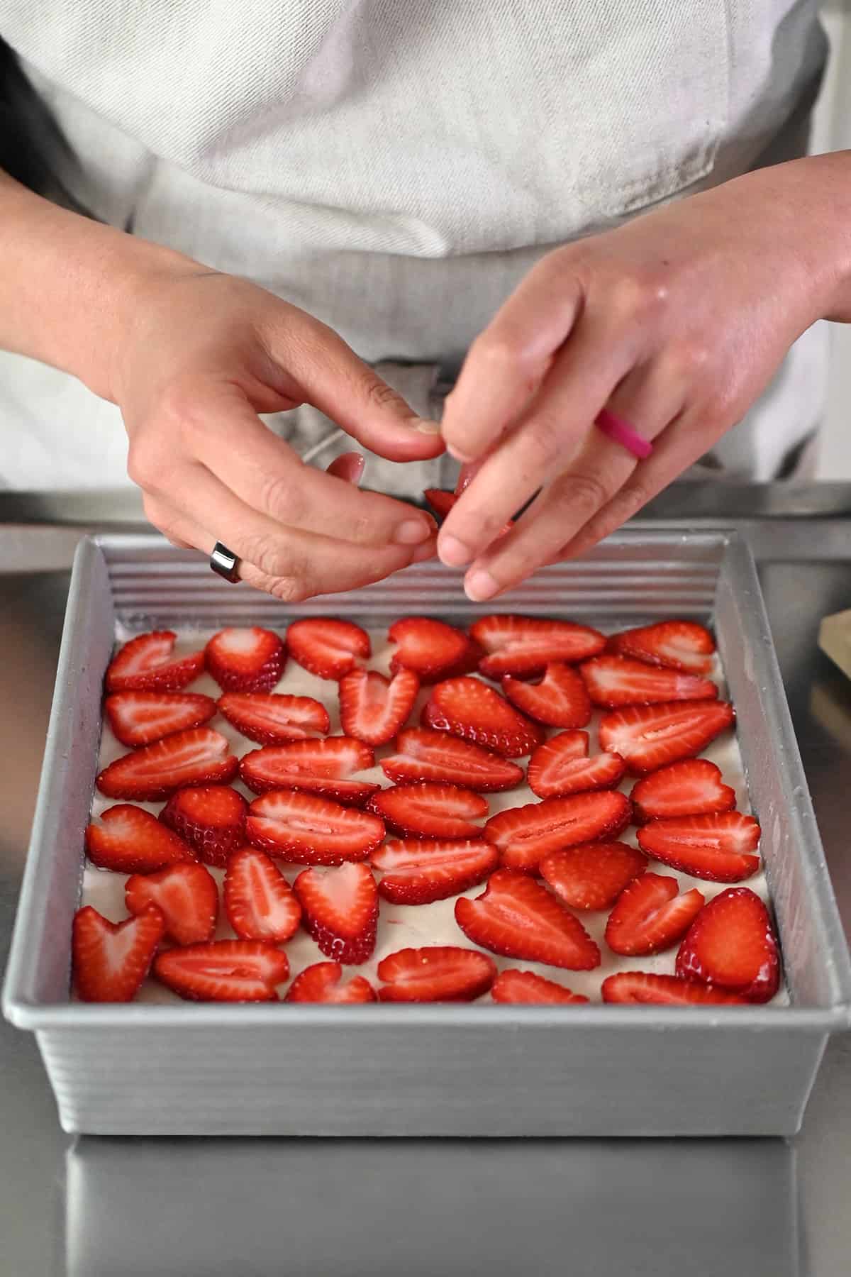 Adding sliced strawberries on the top of a grain-free strawberry pretzel salad.