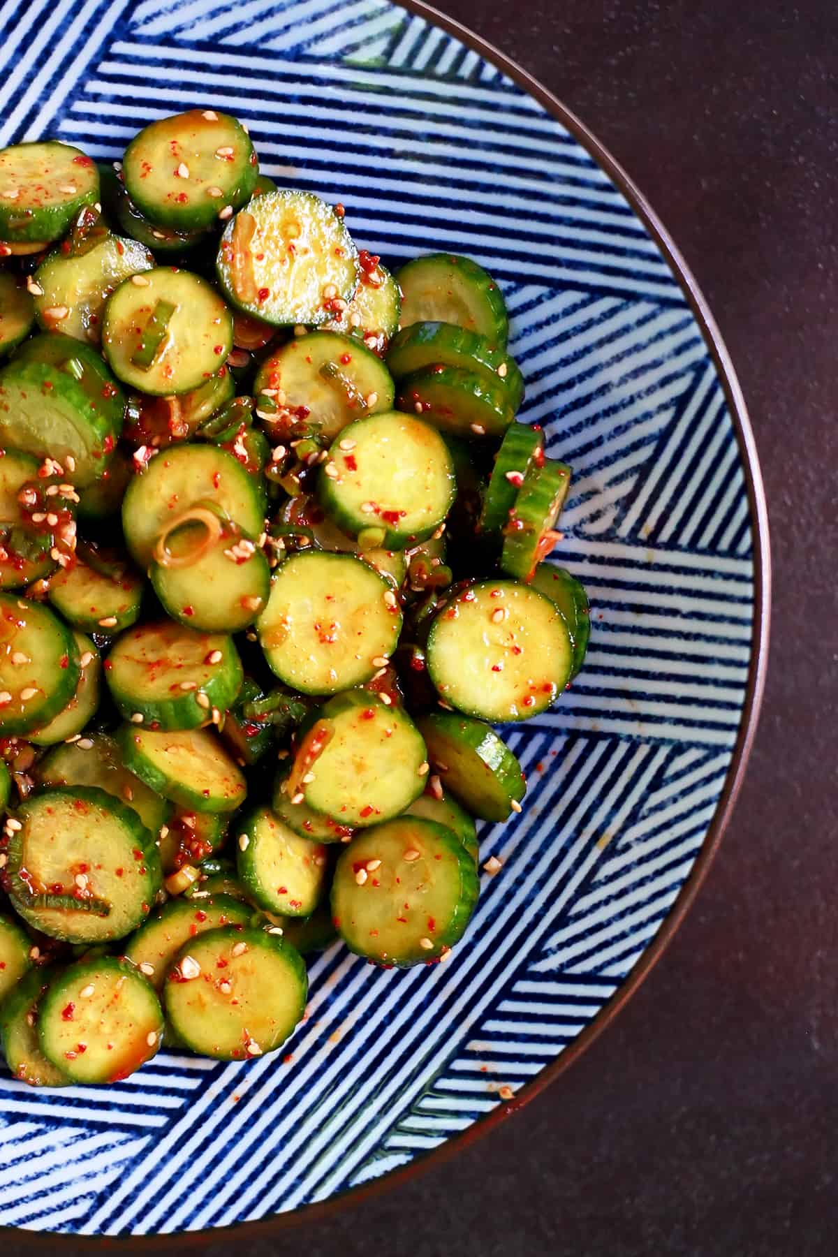 An overhead shot of a blue and white serving bowl with paleo and gluten free Korean cucumber salad.