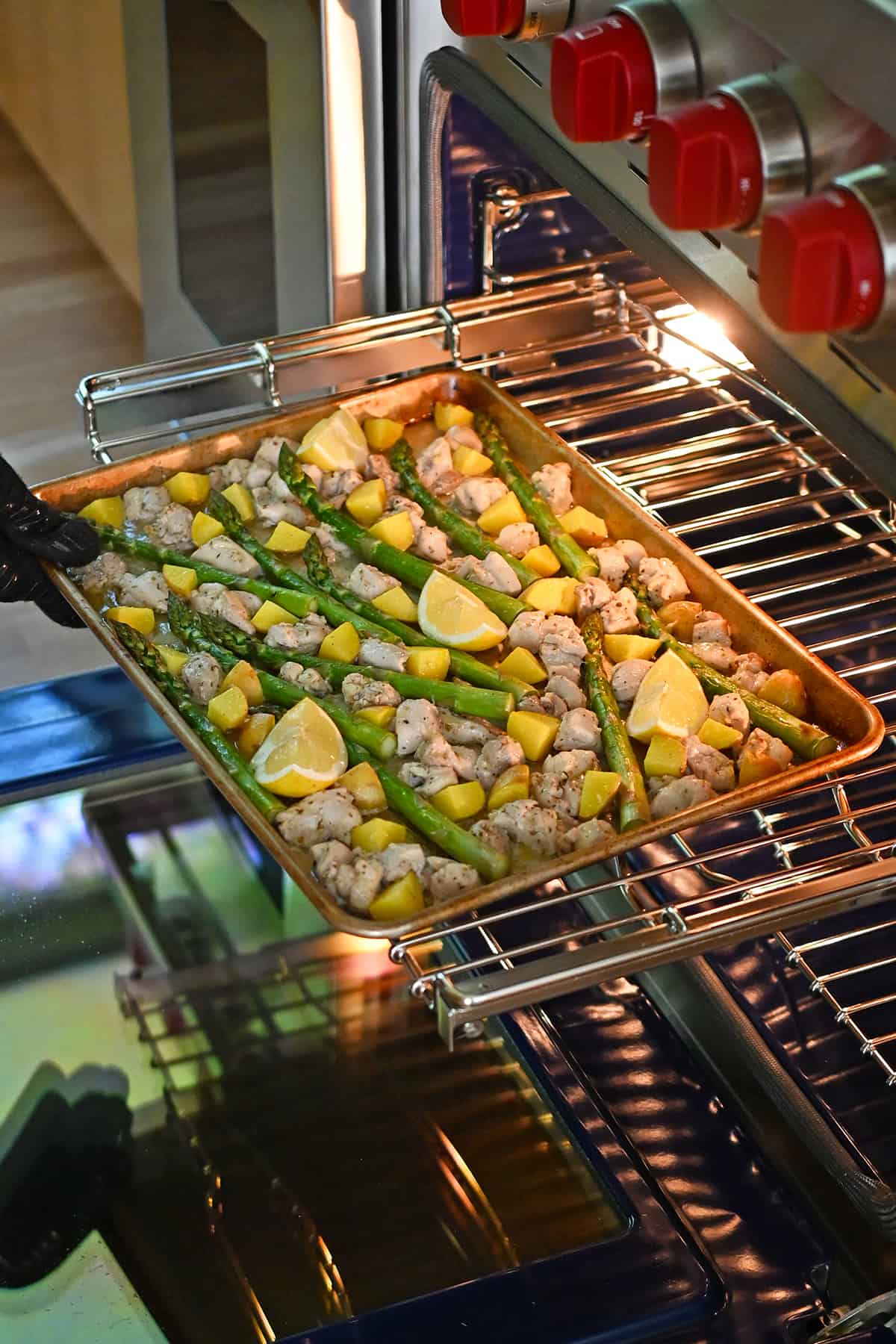 Pulling a Greek sheet pan chicken dinner out of the oven.