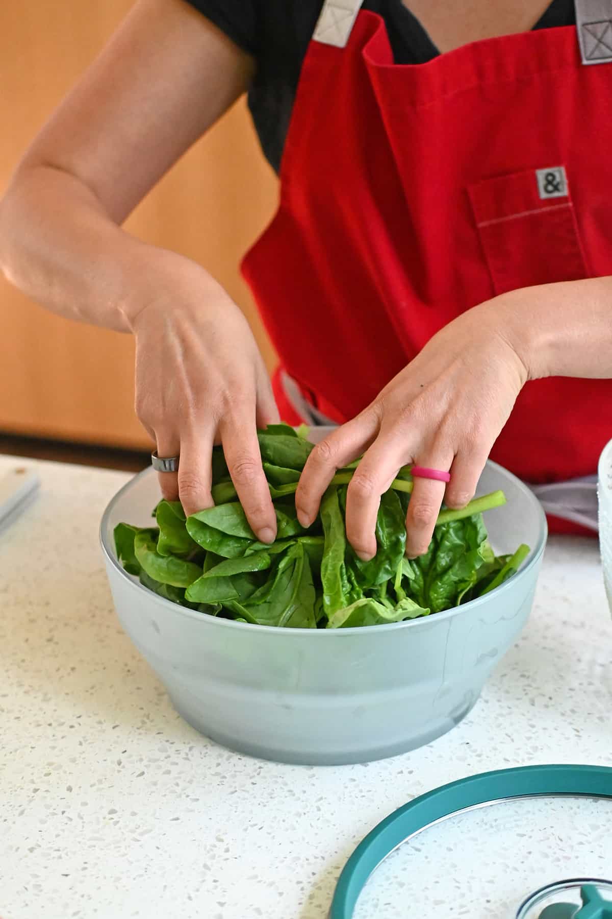 Adding raw spinach to an extra large glass Anyday microwave container.