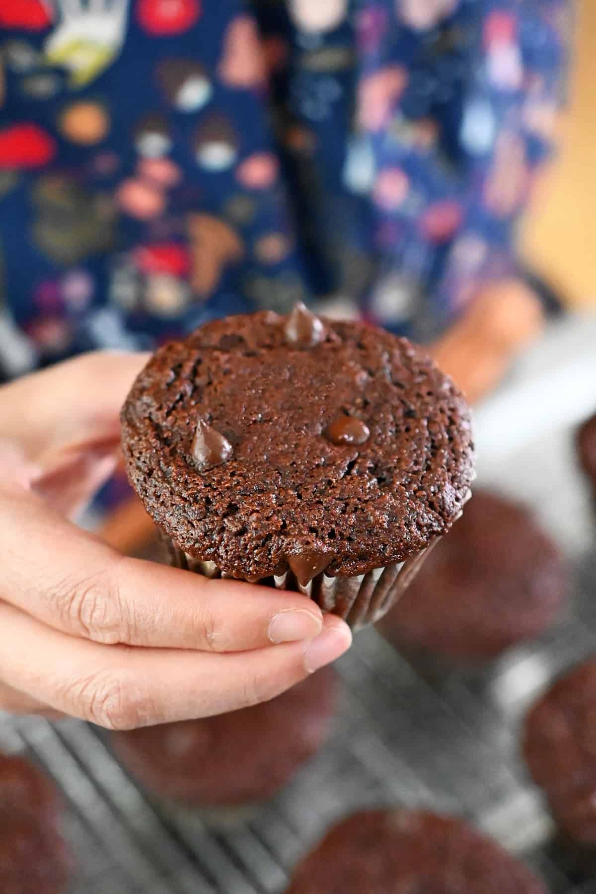A hand is holding a paleo and gluten free chocolate zucchini muffin.