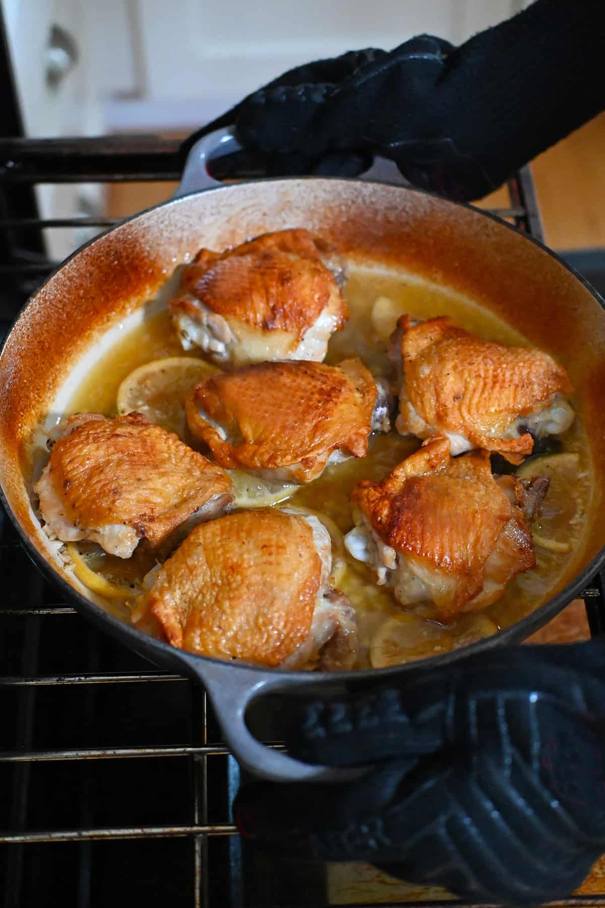 Removing a skillet filled with lemon garlic chicken thighs from the oven.