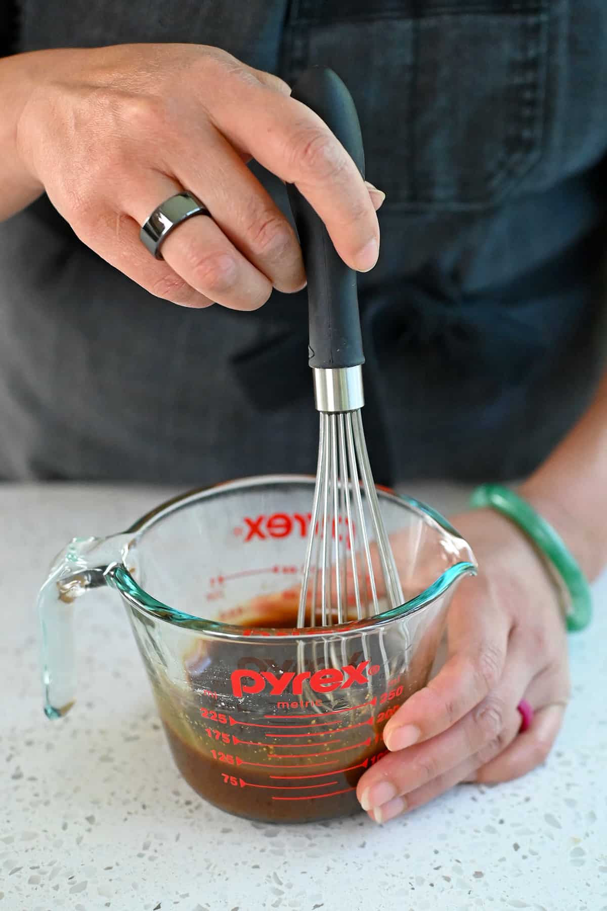 Using a small whisk to combine paleo All Purpose Stir Fry Sauce with arrowroot powder in a liquid measuring cup.