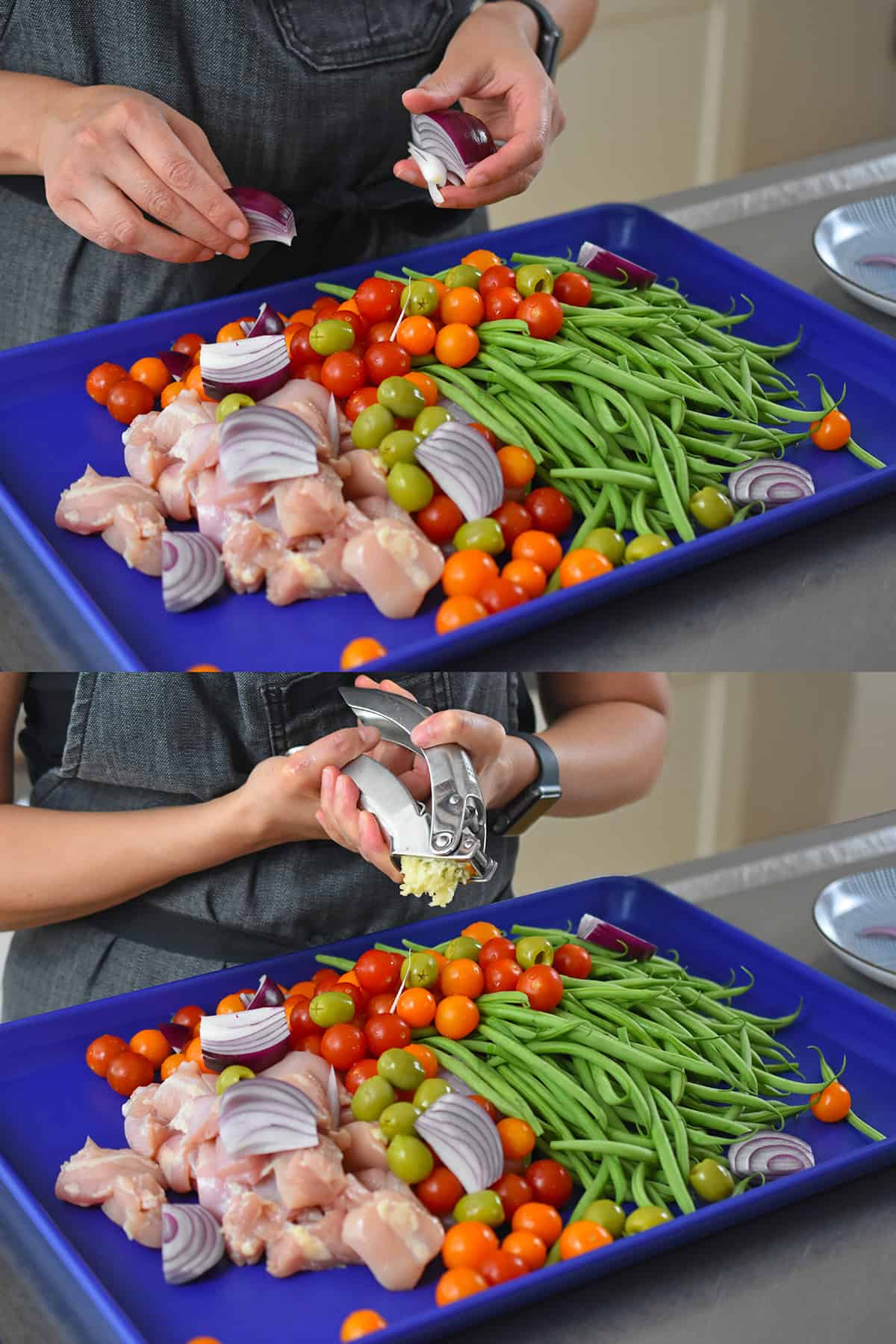 Two shots that show someone adding raw red onion wedges and minced garlic to a blue sheet filled with cubed raw chicken, green beans, and cherry tomatoes.
